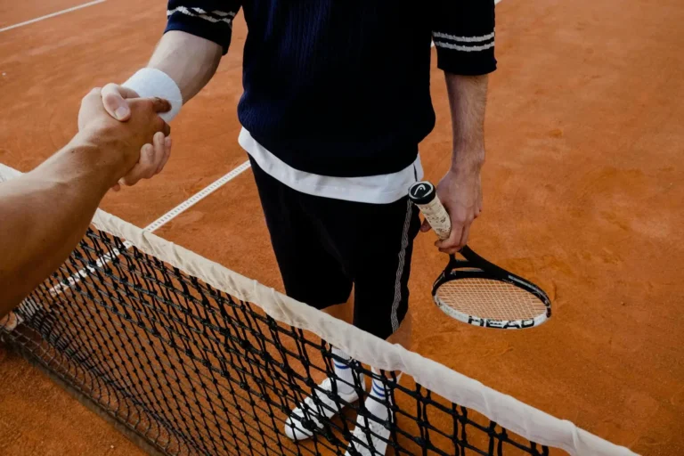 tennis players shaking hands over net