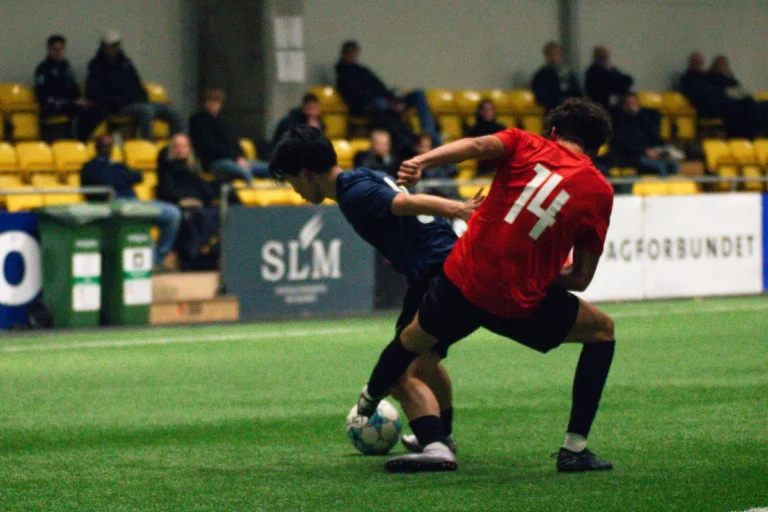 To spillere kæmper om en bold, mens universitetstrænere ser på ved Keystone Sports College Soccer Showcase
