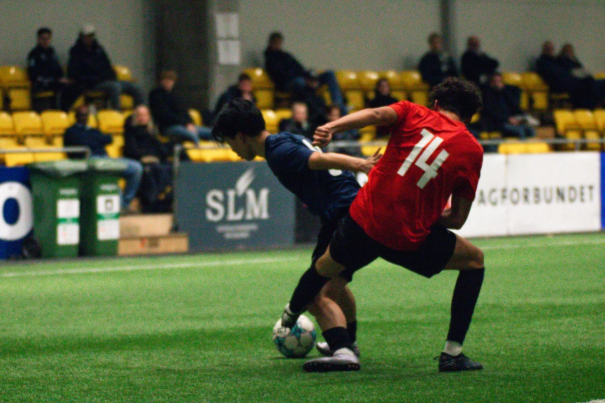 To spillere kæmper om en bold, mens universitetstrænere ser på ved Keystone Sports College Soccer Showcase